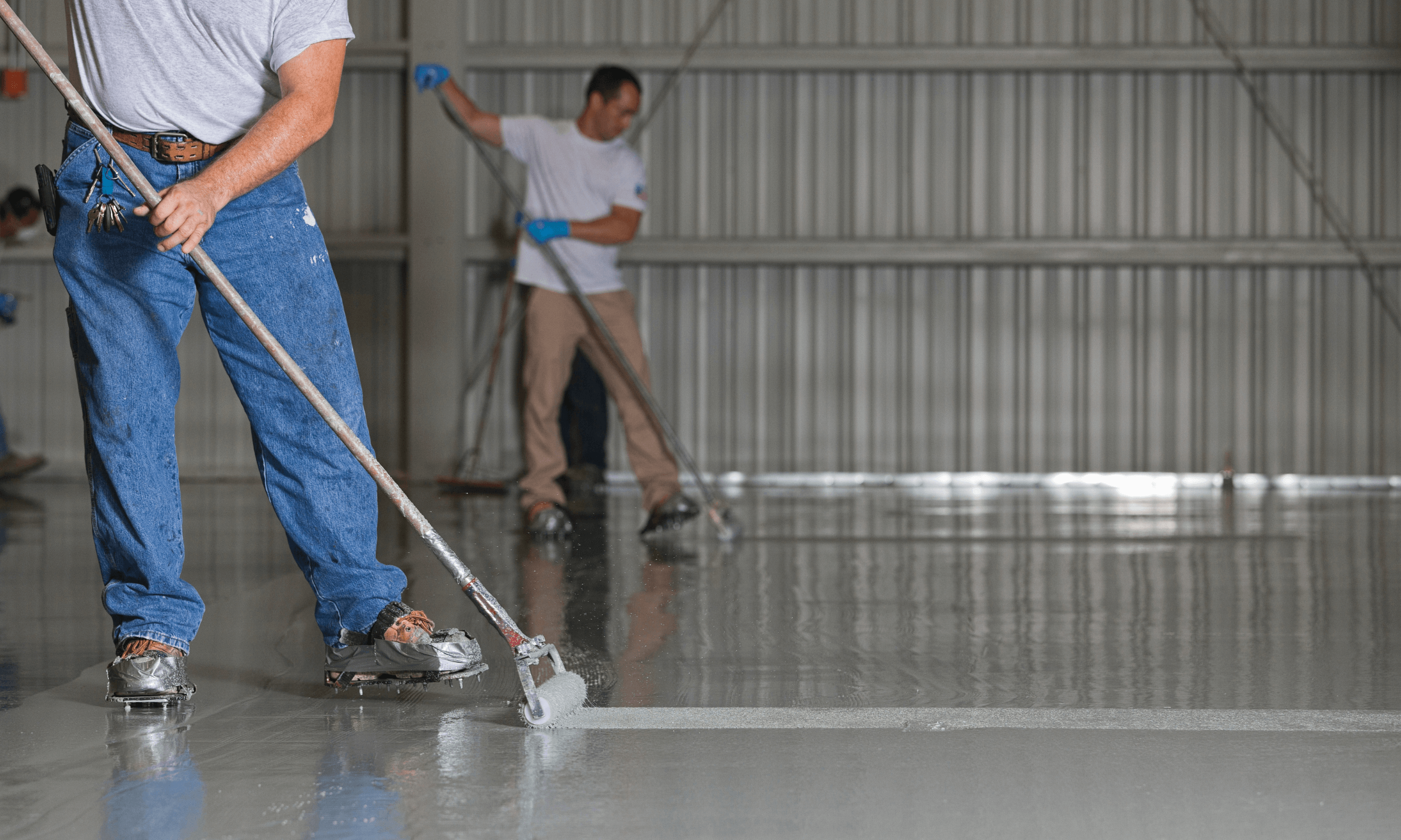 Men applying epoxy on warehouse floor.