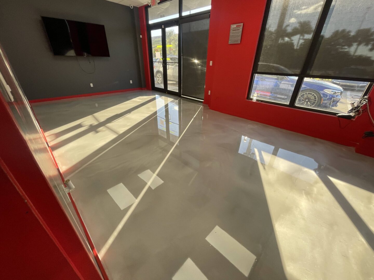 Glossy floor in sunlit red-walled room.